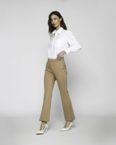 Vista frontal de tres cuartos del pantalón camel de corte recto con pinzas, combinado con camisa blanca y tacones claros