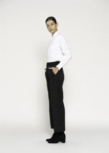 Vista lateral de pantalón negro a rayas con corte ancho, se aprecian bolsillos laterales y cintura con elástico, modelo Formentera