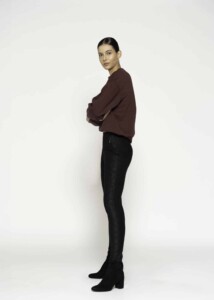 Vista lateral del pantalón negro con textura aterciopelada y cierre, ajuste ceñido completo hasta el tobillo, modelo Formentera