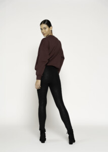 Vista de espalda de pantalón negro ajustado con textura aterciopelada, combinado con sudadera marrón chocolate oversize
