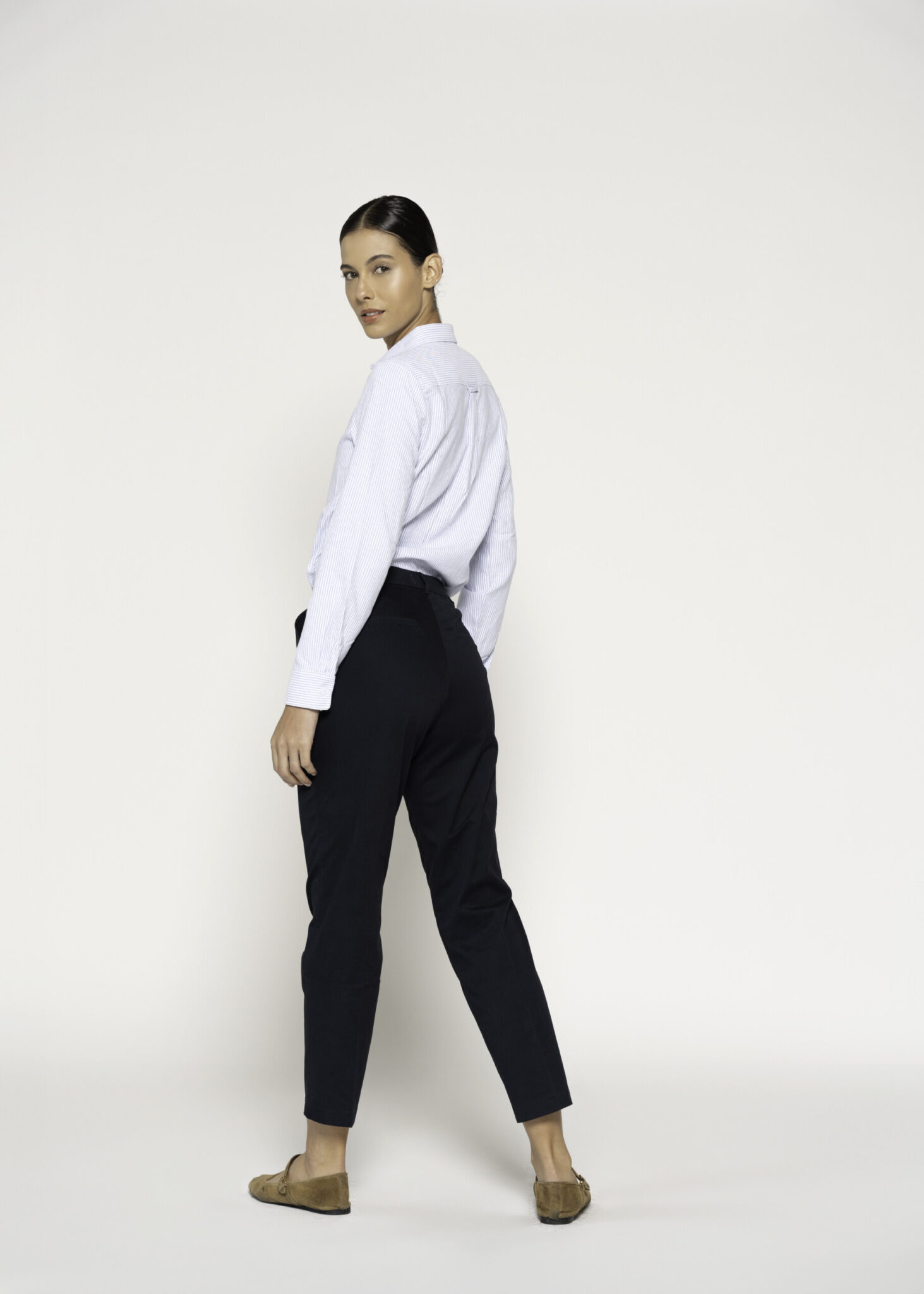 Vista de perfil trasero del pantalón negro recto con pinzas, mostrando corte entallado y largo tobillero, modelo Formentera