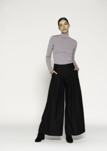 Vista frontal completa de pantalón palazzo negro de tiro alto con pinzas y bolsillos laterales, combinado con polera lila