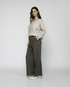 Vista completa de lateral, pantalón palazzo verde militar de tiro alto con pierna ancha y bolsillos, combinado con suéter beige