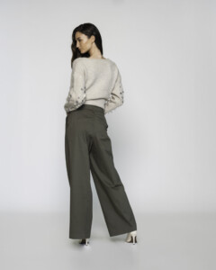 Vista trasera completa del pantalón palazzo verde militar de corte ancho combinado con suéter beige con bordados en mangas