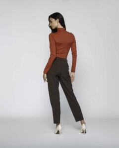 Vista trasera de pantalón recto a cuadros en tono café oscuro, combinado con top terracota de cuello alto y tacones blancos