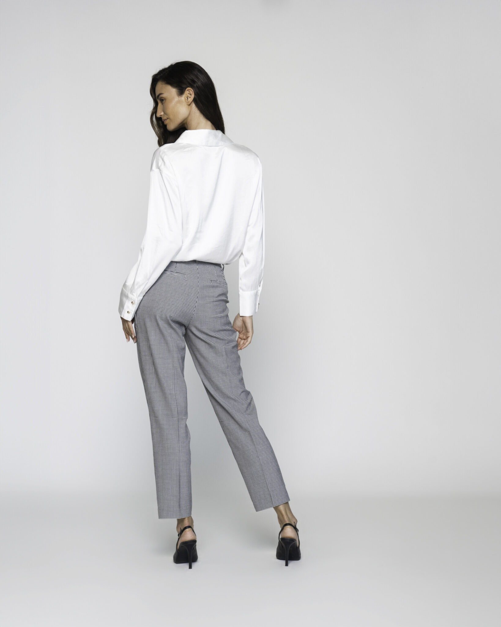 Vista de espalda del pantalón recto a cuadros grises con camisa blanca, destacando el ajuste y caída del tejido modelo Formentera