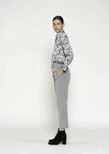 Vista lateral de pantalón recto gris con pinzas, manos en bolsillos laterales, combinado con camisa estampada, modelo Formentera