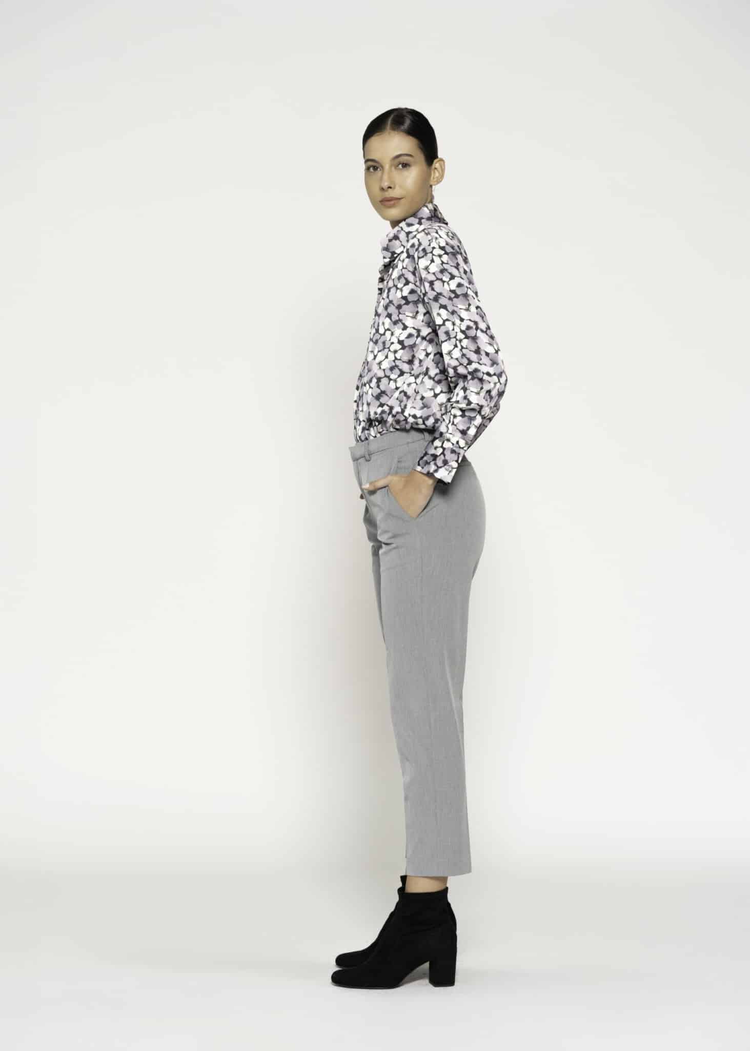 Vista lateral de pantalón recto gris con pinzas, manos en bolsillos laterales, combinado con camisa estampada, modelo Formentera