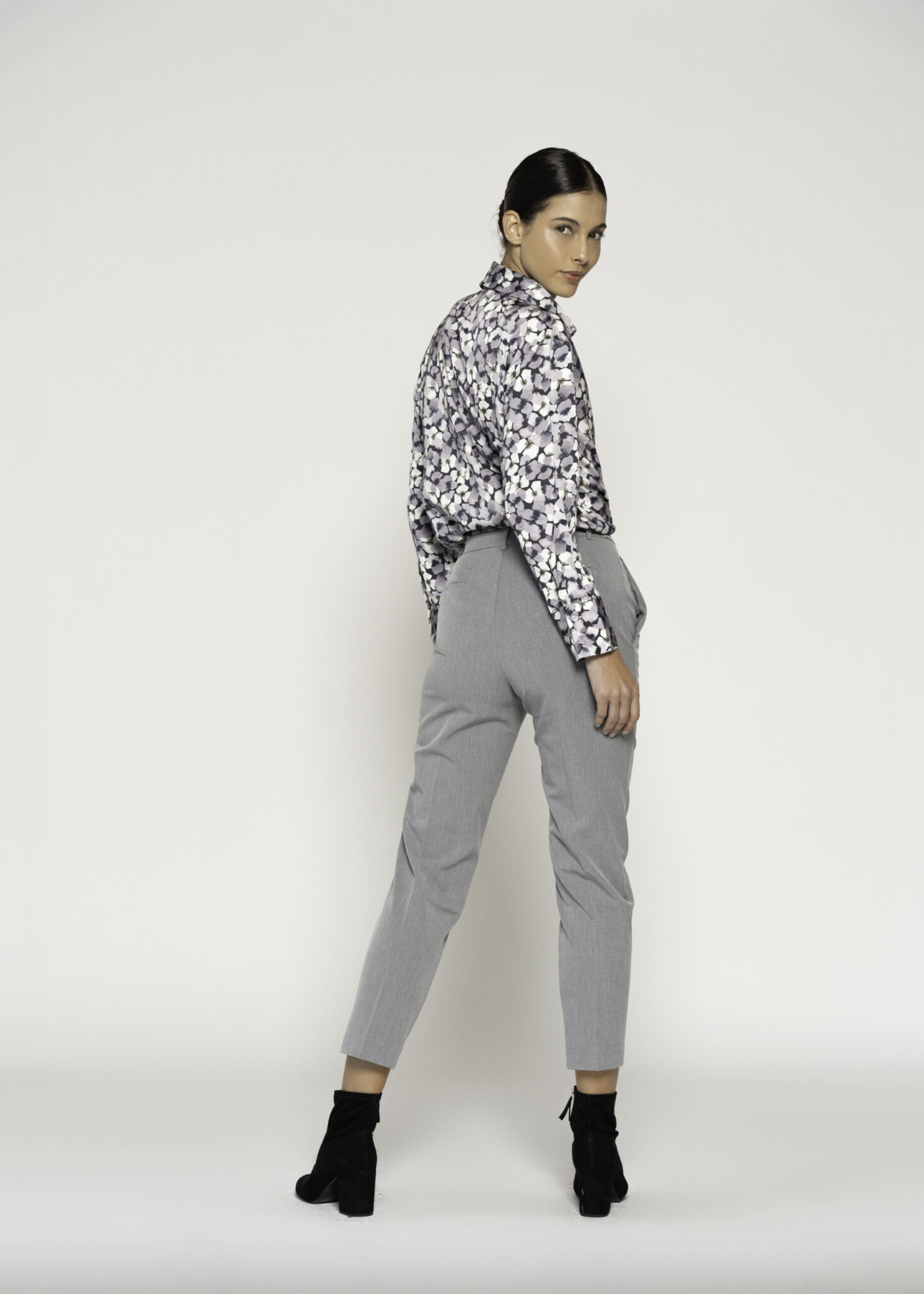 Vista trasera de pantalón recto gris con pinzas combinado con camisa estampada en blanco y negro, modelo Formentera