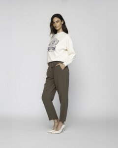 Vista lateral de pantalón verde militar con cordón ajustable en cintura, bolsillos frontales visibles y corte recto, combinado con sudadera blanca y tacones modelo Formentera