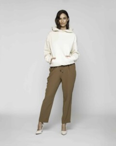 Vista completa frontal de conjunto casual con polerón crudo oversize con capucha y pantalón camel, modelo Formentera
