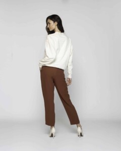 Vista posterior de polerón crudo oversize con pantalón marrón chocolate y tacones beige, mostrando caída holgada del diseño