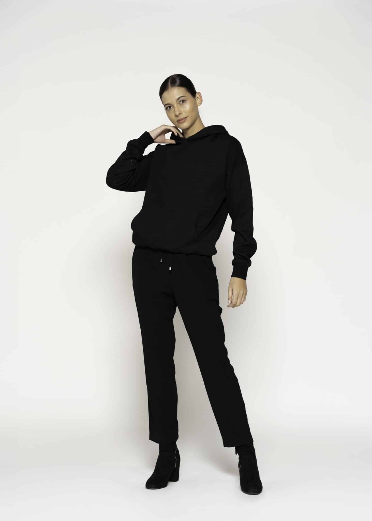 Vista completa del conjunto negro: polerón con capucha y pantalón jogger con cordón ajustable, modelo Formentera
