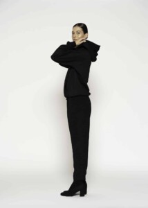 Vista lateral completa de polerón negro oversize con capucha y pantalones a juego, modelo Formentera en postura pensativa