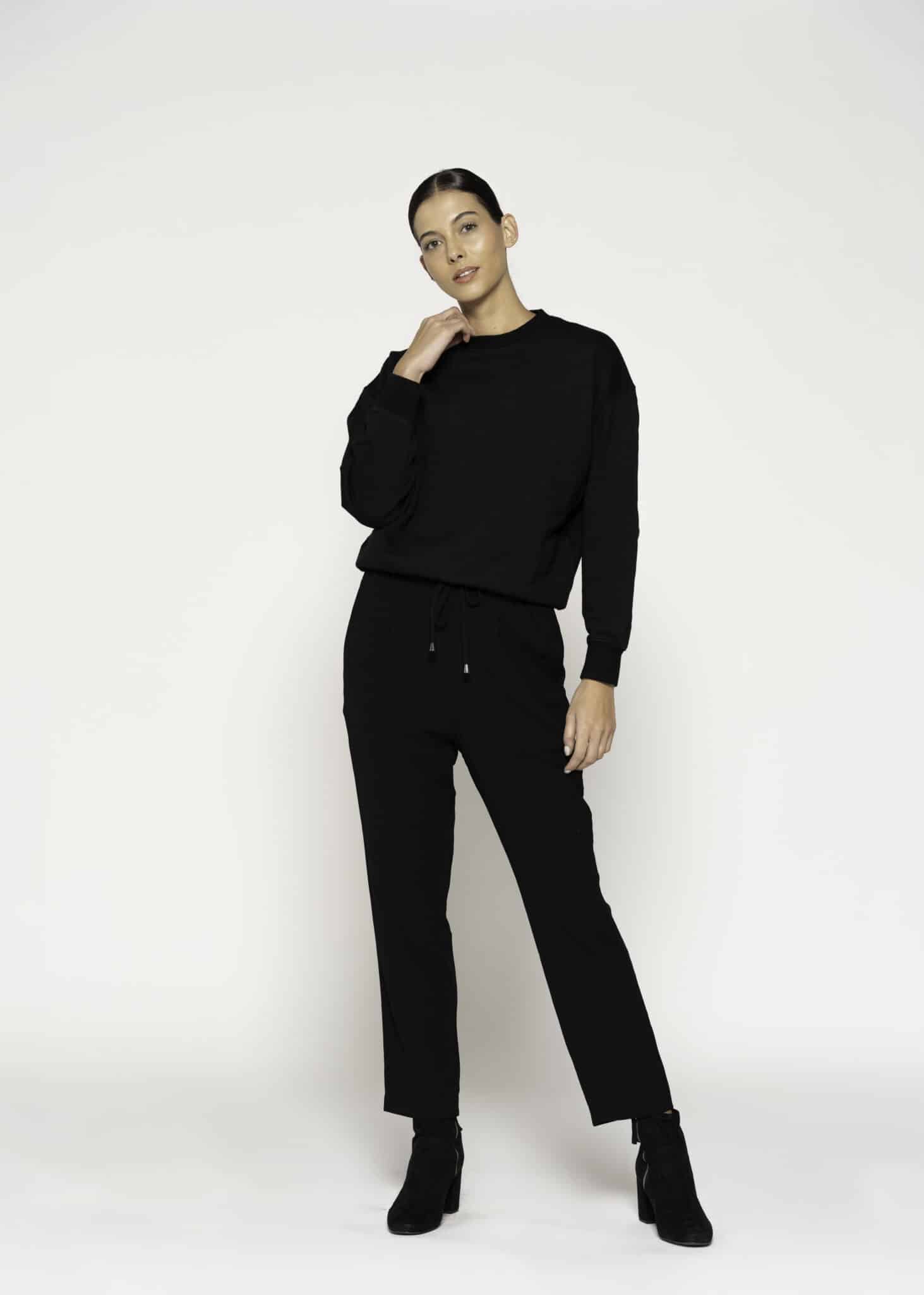 Vista completa de conjunto negro con polerón oversize de cuello redondo y pantalón recto con cordón, modelo Formentera