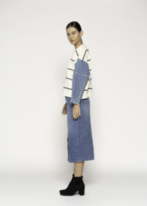 Vista lateral de sweater tejido a rayas con mangas de mezclilla azul, combinado con vestido denim midi, modelo Formentera