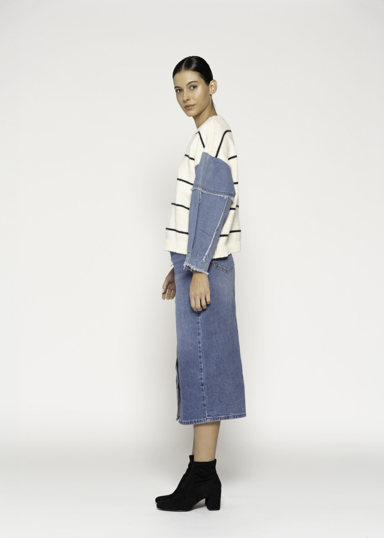 Vista lateral de sweater tejido a rayas con mangas de mezclilla azul, combinado con vestido denim midi, modelo Formentera