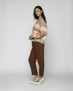 Vista lateral de sweater tejido a rayas con degradé en tonos rosa, amarillo y verde, combinado con pantalón marrón y stilettos blancos