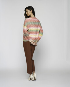 Vista de espalda completa del sweater tejido con franjas horizontales degradé en rosa, verde, amarillo y crema, combinado con pantalón marrón