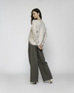 Vista trasera de sweater beige con lentejuelas en las mangas y pantalón palazzo verde oliva, modelo Formentera