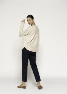 Vista de perfil lateral de sweater beige con motas de colores, tejido de punto oversize con cuello redondo, combinado con pantalón negro
