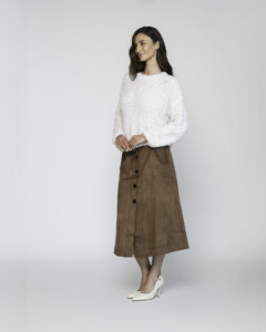 Vista completa de sweater blanco textura bouclé con falda midi de ante camel con botonadura frontal, modelo Formentera