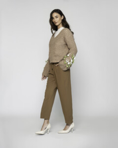 Vista de perfil del sweater tejido camel con bordado floral en puños, combinado con pantalón caqui y camisa blanca de cuello visible