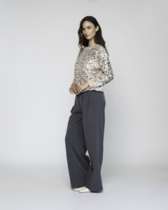 Vista lateral de sweater tejido beige claro con estampado de puntos negros, cuello redondo y manga larga, combinado con pantalón amplio gris, modelo Formentera