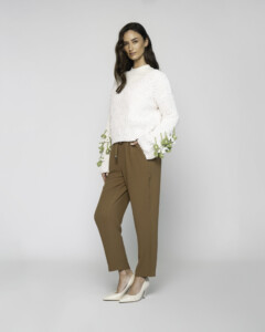 Vista lateral de tres cuartos del sweater tejido crudo con bordado floral verde en mangas, combinado con pantalón caqui