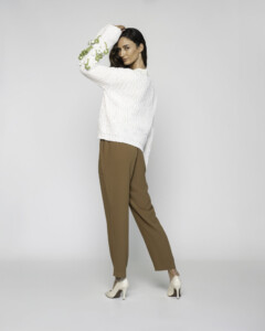 Vista trasera de sweater tejido crudo con bordado floral en mangas y pantalón camel, modelo Formentera de perfil