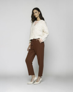 Vista lateral del sweater tejido crudo con detalle de cordón cruzado en escote y rayas naranjas en mangas, modelo Formentera