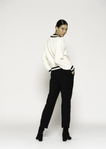 Vista de espalda del sweater tejido crudo con ribetes negros en cuello y puños, combinado con pantalón negro