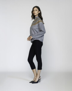 Vista lateral de sweater gris con guardas zigzag en tonos beige y negro sobre hombros, cuello alto, combinado con pantalón negro y stilettos