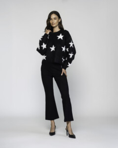 Vista completa de conjunto con sweater negro de estrellas blancas y pantalón negro, modelo en pose frontal sobre fondo claro