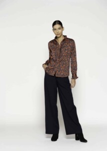 Vista completa de camisa con estampado floral naranja sobre fondo oscuro y pantalón negro ancho, modelo Formentera