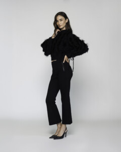 Vista lateral de sweater negro cropped con textura peluda, mangas voluminosas y lazos ajustables, modelo Formentera
