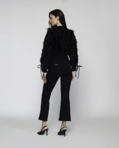 Vista de espalda del sweater negro con textura peluda, mangas con lazos ajustables en puños, modelo Formentera