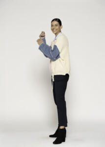 Vista lateral de sweater tejido con bloques crema y rosa, mangas desmontables de mezclilla azul y cordón de ajuste visible