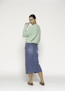 Vista de espalda de sweater tejido verde menta con textura esponjosa, combinado con falda denim azul midi, modelo Formentera