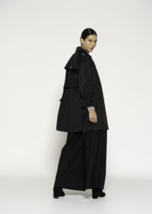 Vista lateral de trench negro con cuello amplio, cinturón en la cintura y pantalón palazzo, modelo Formentera