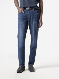Jeans slim fit azul oscuro de PuroEgo en tres cuartos: se ve el costado, el bolsillo delantero y el desgaste del muslo.