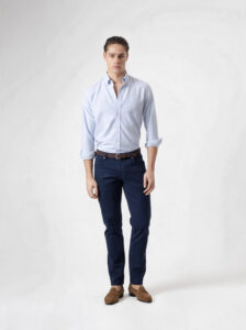 Pantalón cinco bolsillos azul marino de PuroEgo, de cuerpo entero y de frente, con camisa celeste, cinturón café y mocasines de gamuza.