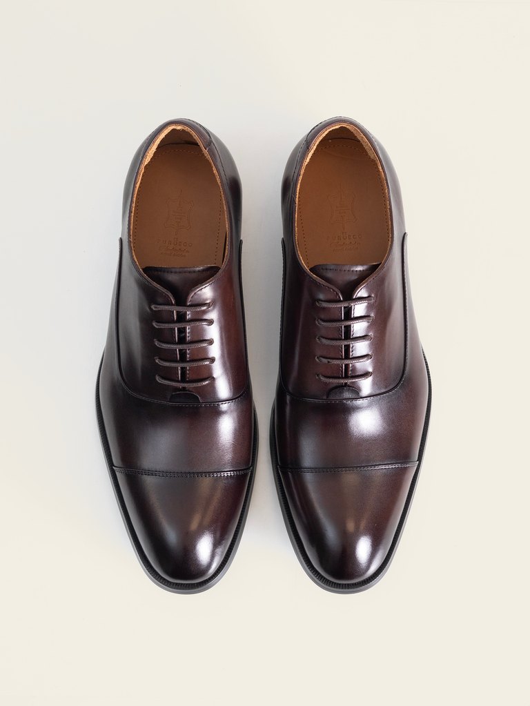 El par de zapatos oxford burdeo de PuroEgo visto desde arriba, con la puntera con costura y la plantilla de piel
