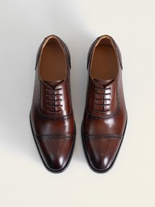 El par de zapatos oxford café de PuroEgo visto desde arriba, con el picado de la puntera y la plantilla de piel