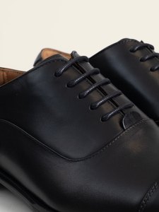 Detalle del cordonaje y de la piel del empeine del zapato oxford negro PuroEgo