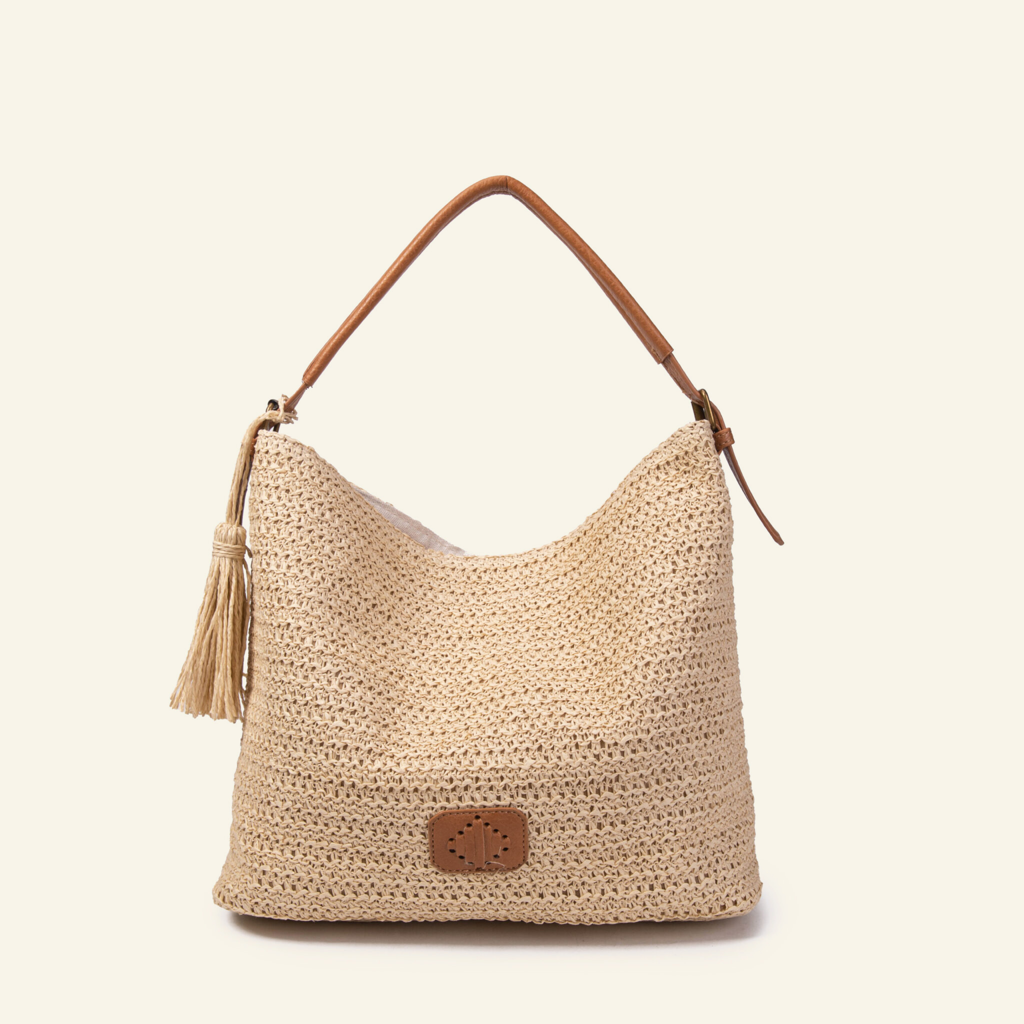 Cartera hobo de rafia beige con tira de ecocuero café de Formentera, de frente: se ven el tejido calado, la borla y la tira completa.
